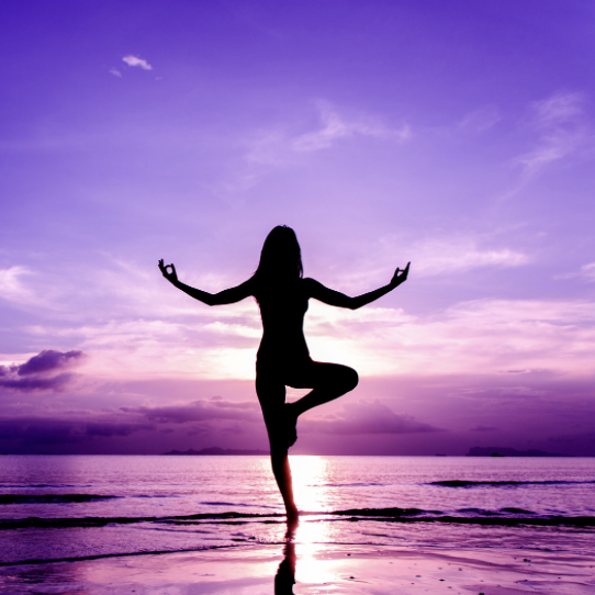 A woman practicing yoga at sunset, symbolizing the union of physical and mental well-being.